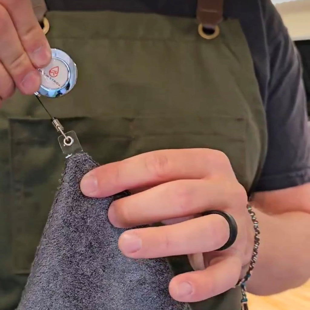 A barista showing a close up of a Dry in Stride towel and clip. 