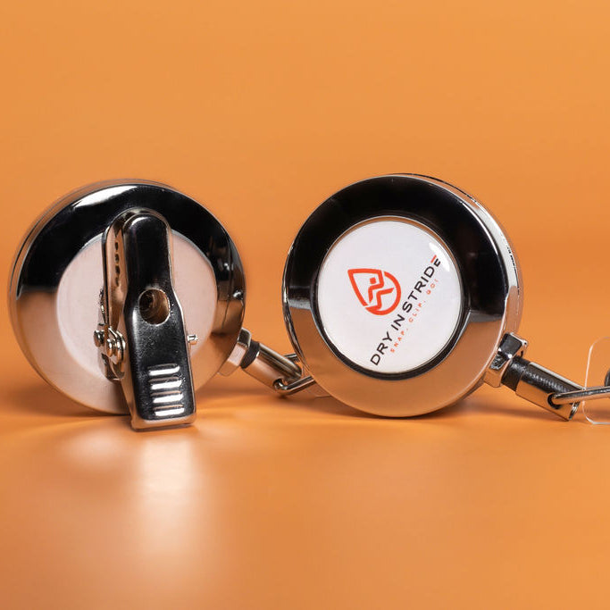 Front and Back of Dry in Stride retractable clip with a brand logo on an orange background