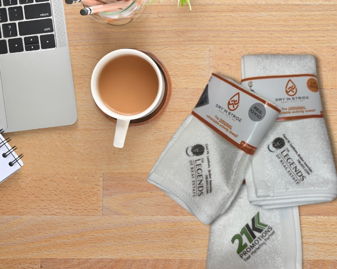 Laptop, cup of tea, and custom logo Dry in Stride towel sets on a wooden desk