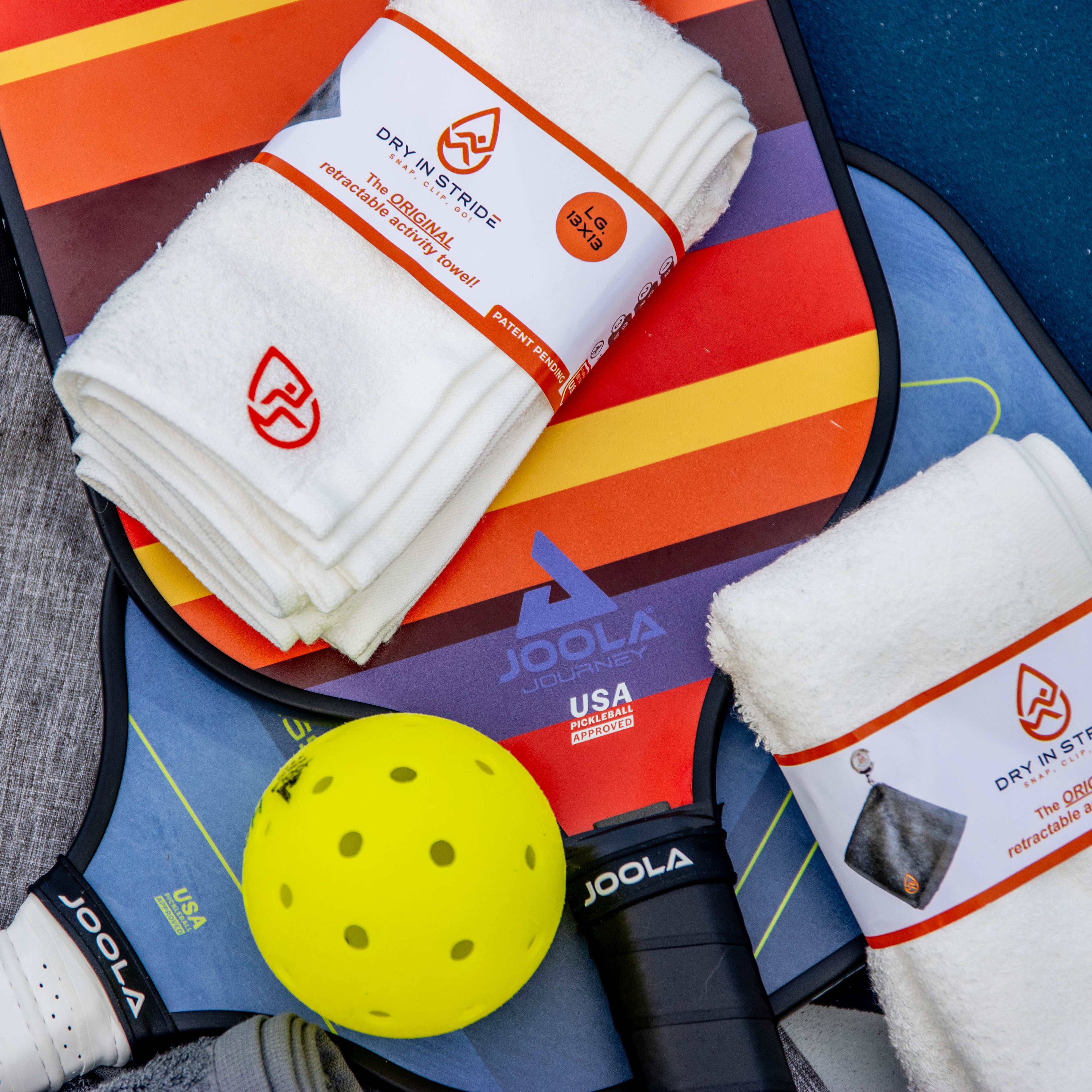 Pickleball paddle, yellow ball, and Dry in Stride towels on a colorful background