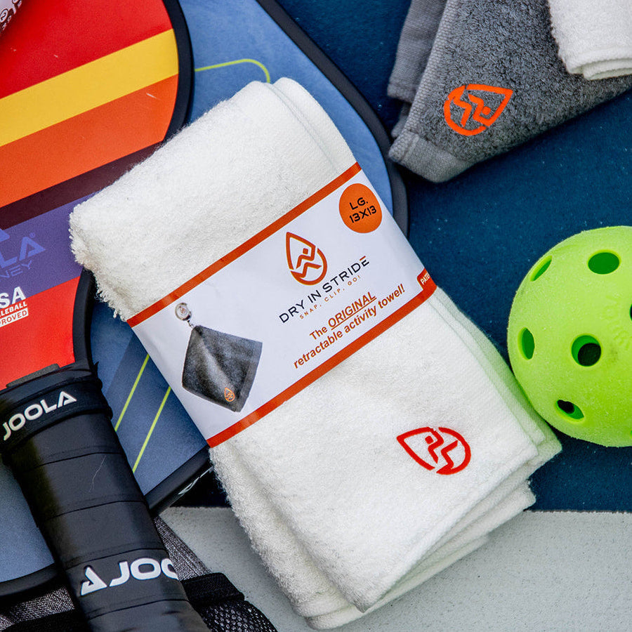 Collection of pickleball equipment including balls, rackets, and towels on a colorful background.